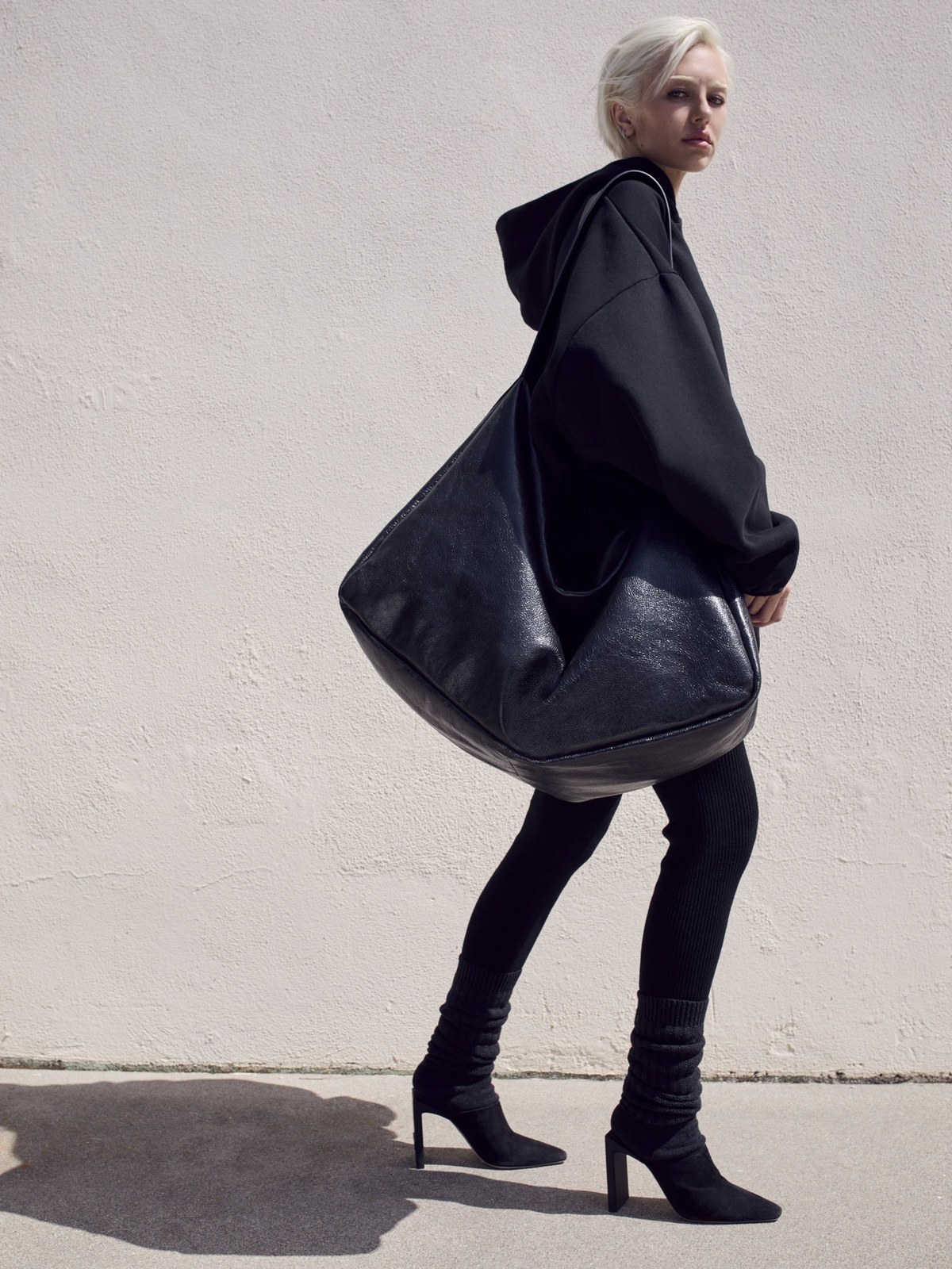 Woman in black carrying a large bag in the ESSENTIALS campaign