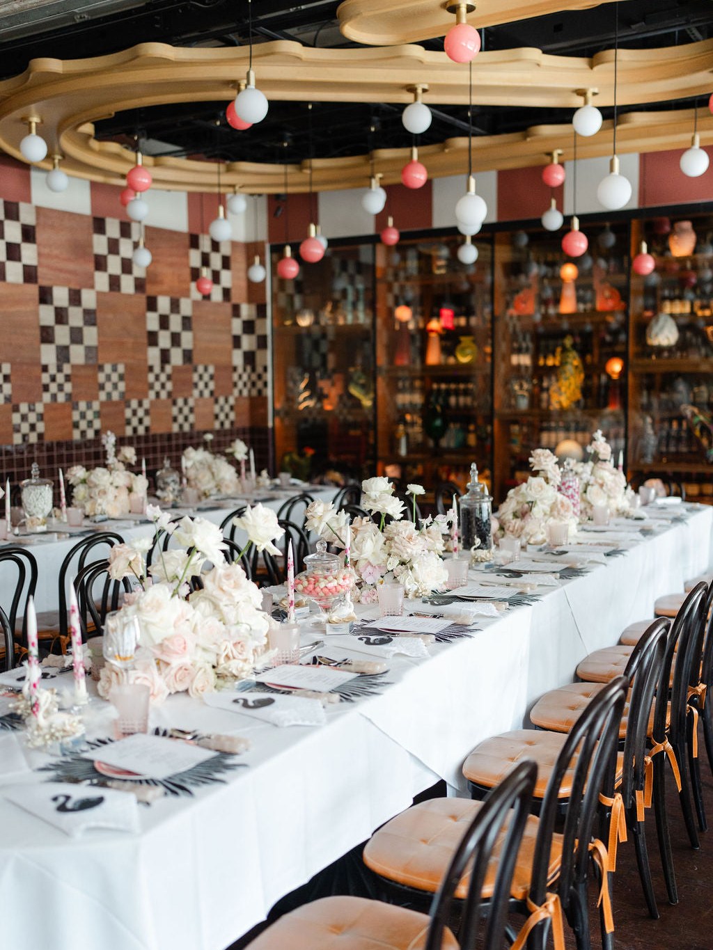 Long floral dinner table in a patterned restaurant setting with pink and white balloons