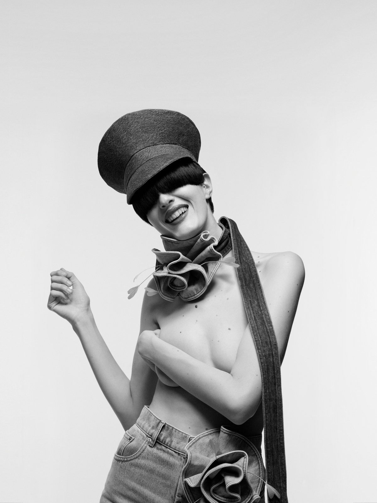 Black-and-white portrait with a sculptural hat and ruffled neck detail