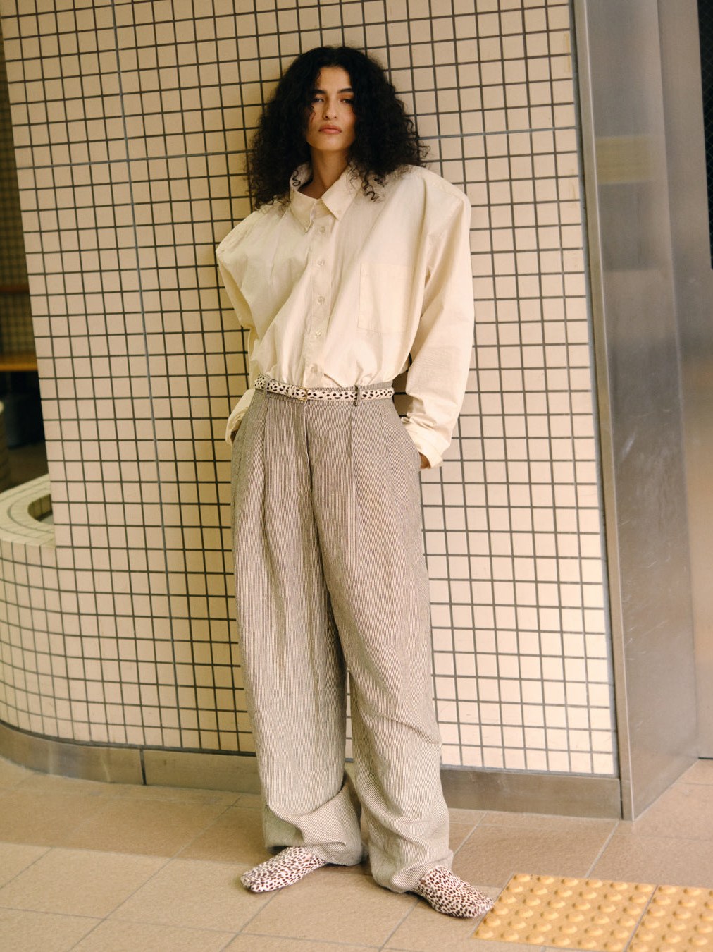 Model in a white shirt and relaxed trousers wearing patterned flats