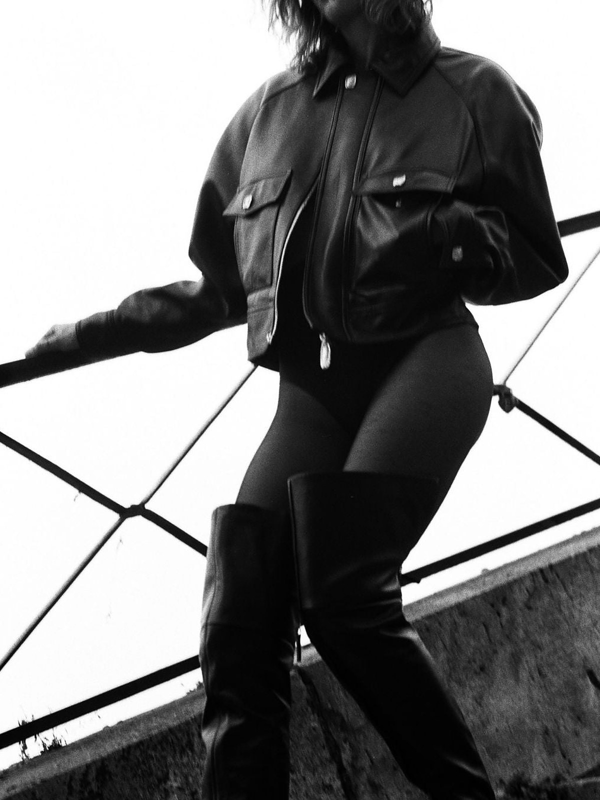 Black and white model in a cropped leather jacket and thigh high boots on stairs