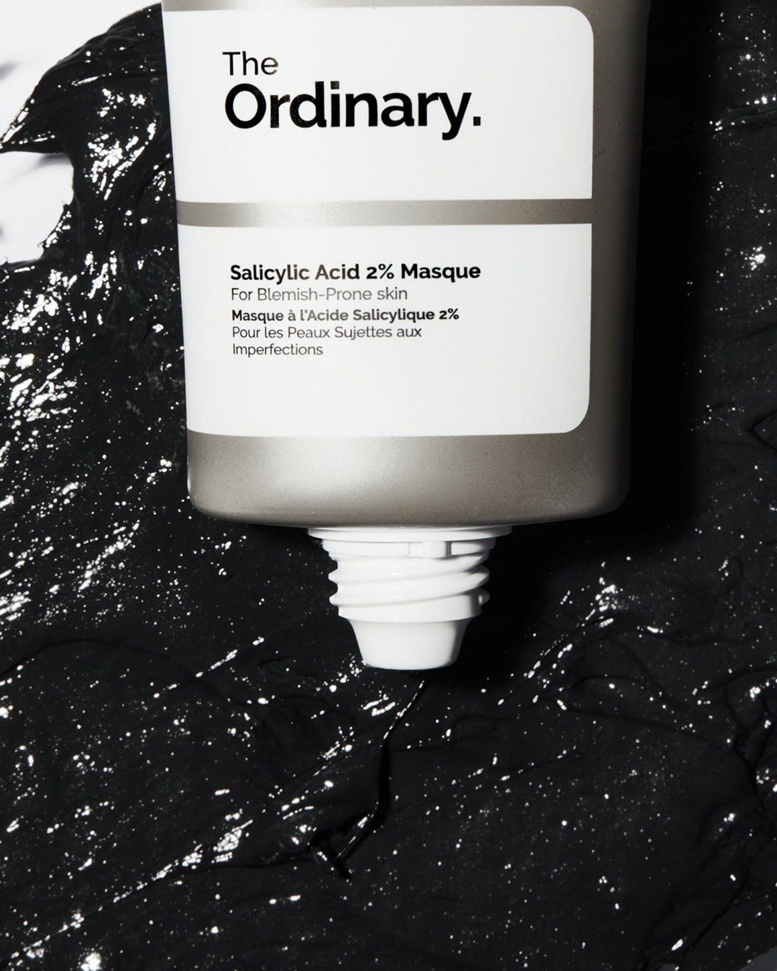 The Ordinary Salicylic Acid 2% Masque tube resting in a smear of black charcoal mask