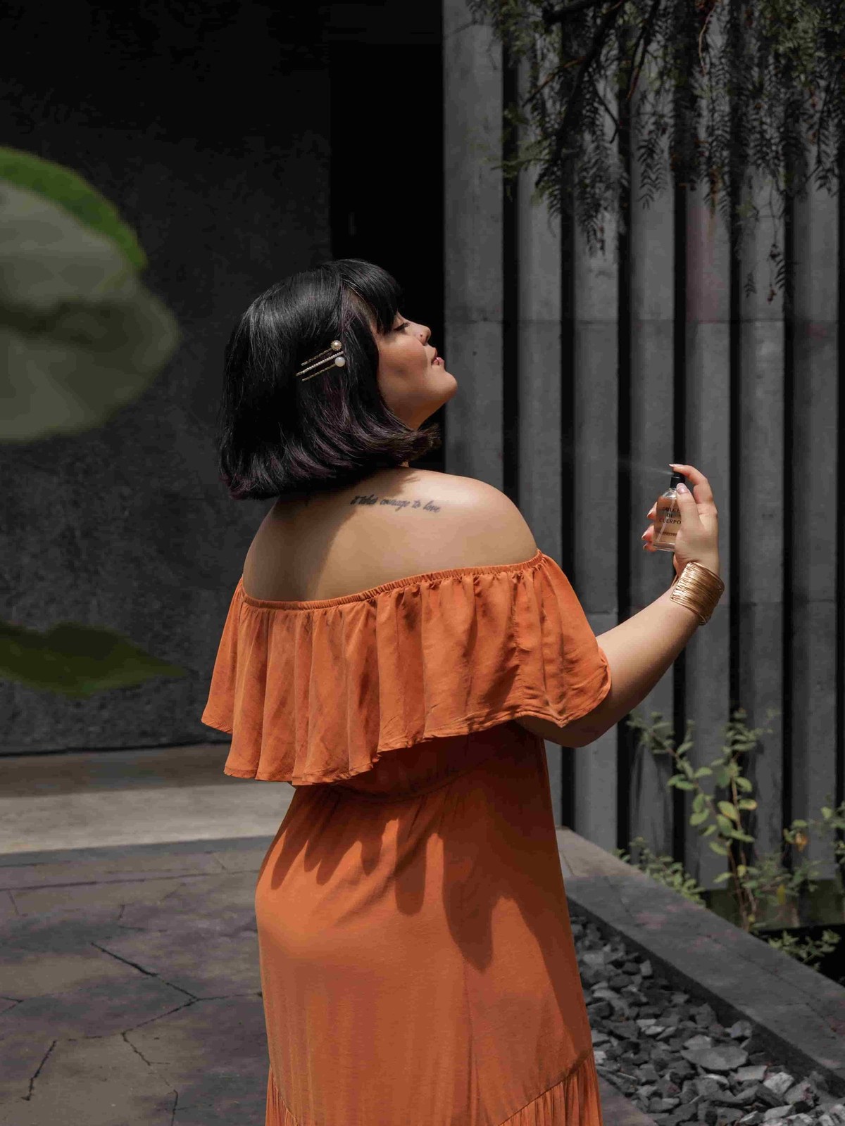 Woman in an orange dress stands in a dark courtyard with her profile visible