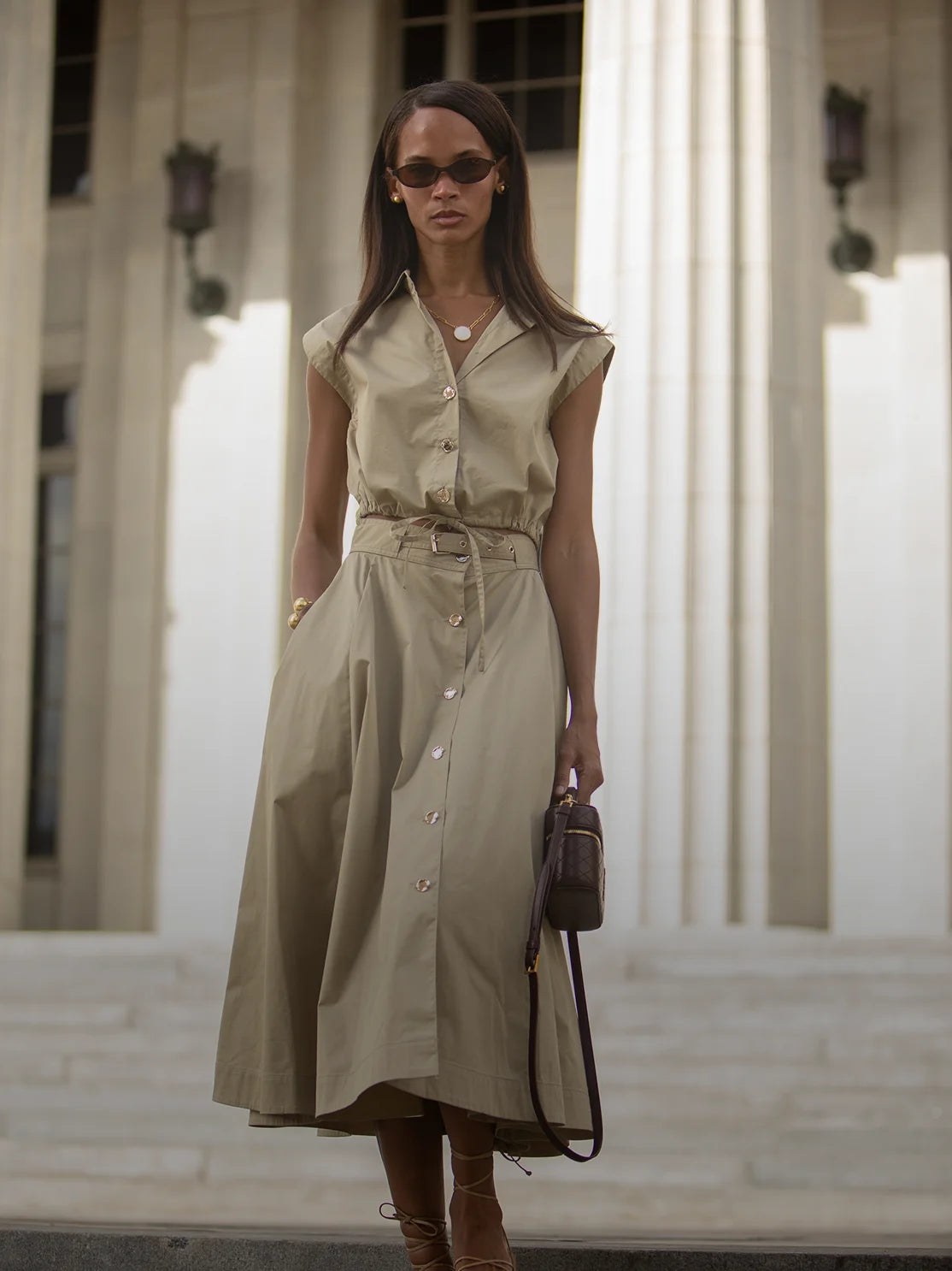 Model in a khaki belted midi dress outside a columned building