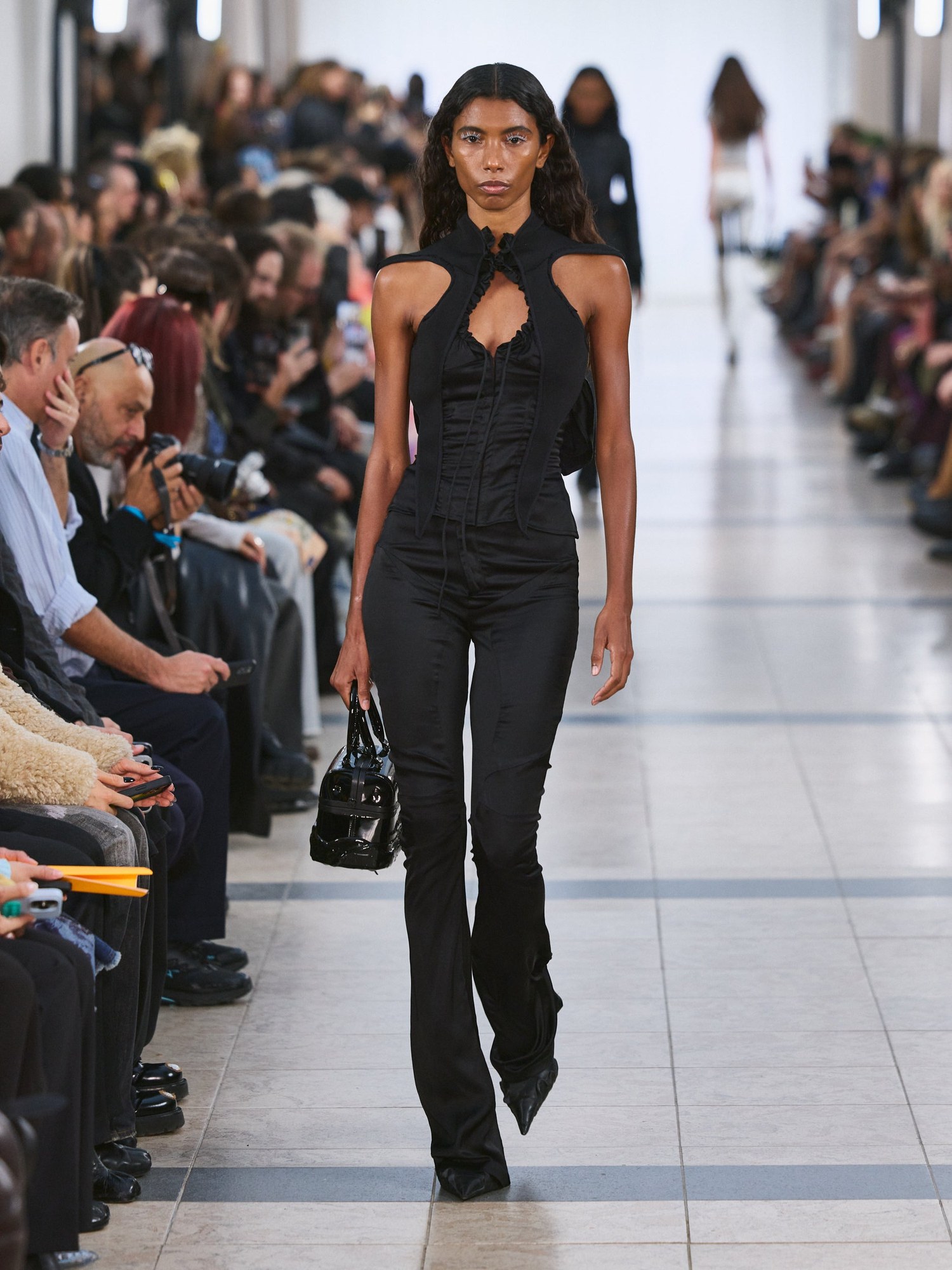 Runway model in a black halter cutout top and flared trousers