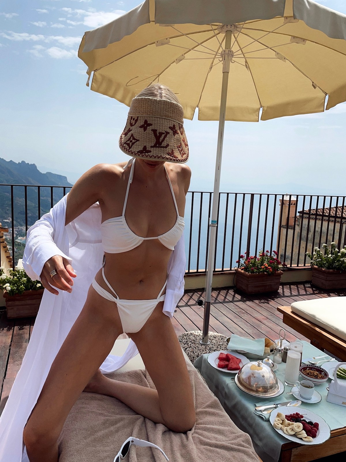 Leonie Hanne in a white Lovewave bikini with a cover-up under a terrace umbrella