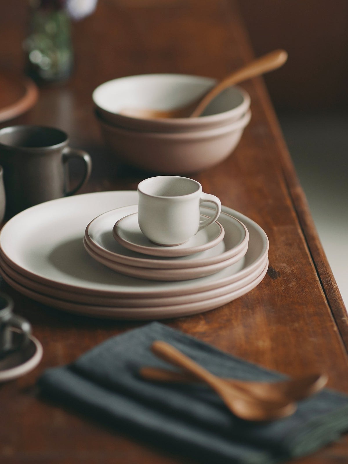 Ceramic plates, bowls, and cups arranged on a wooden table