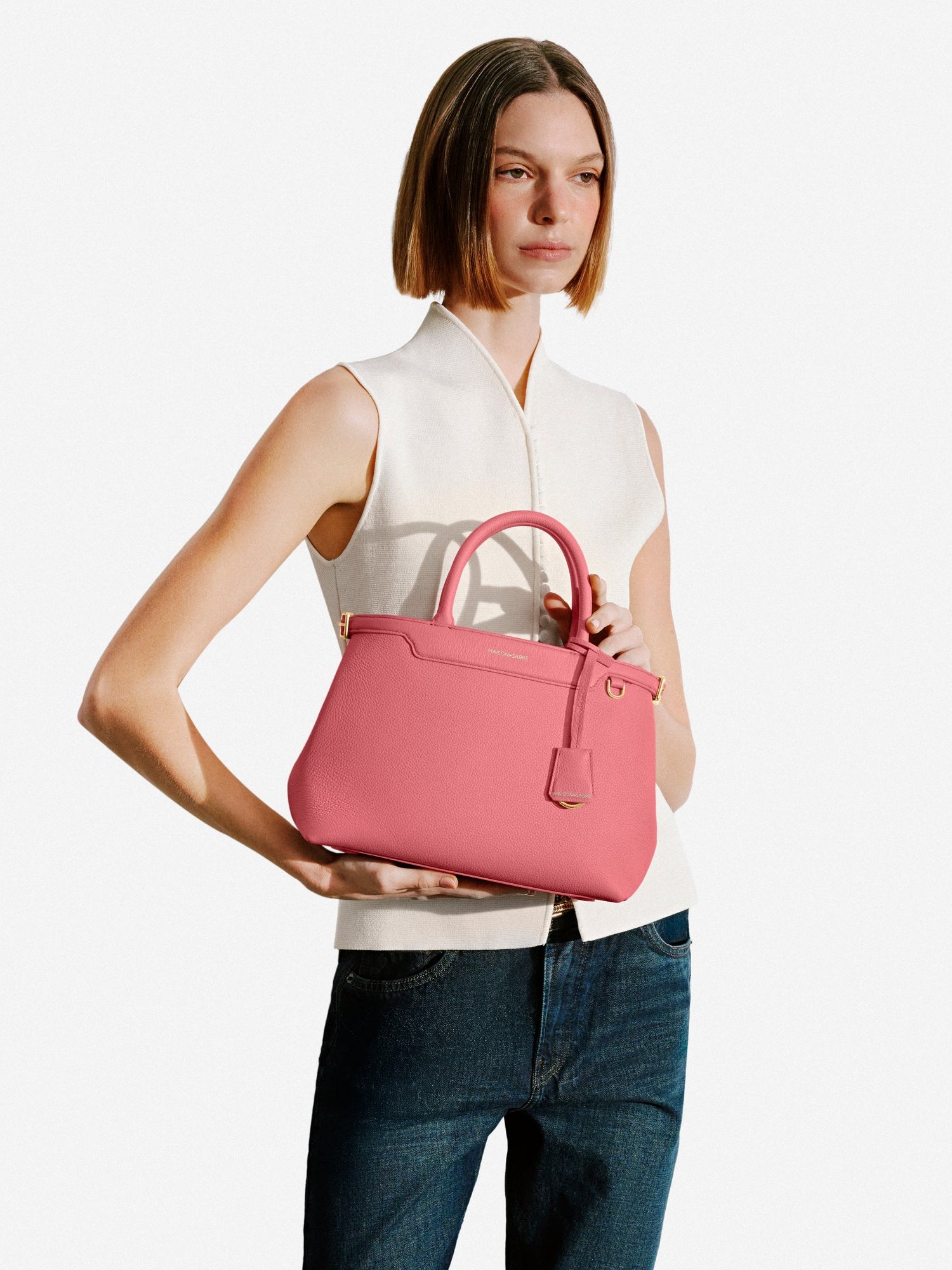 Model carrying the pink Palais bag by hand against grey
