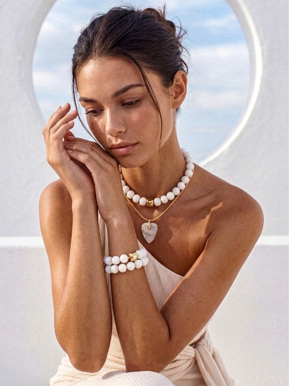Model in white wearing layered pearl jewelry