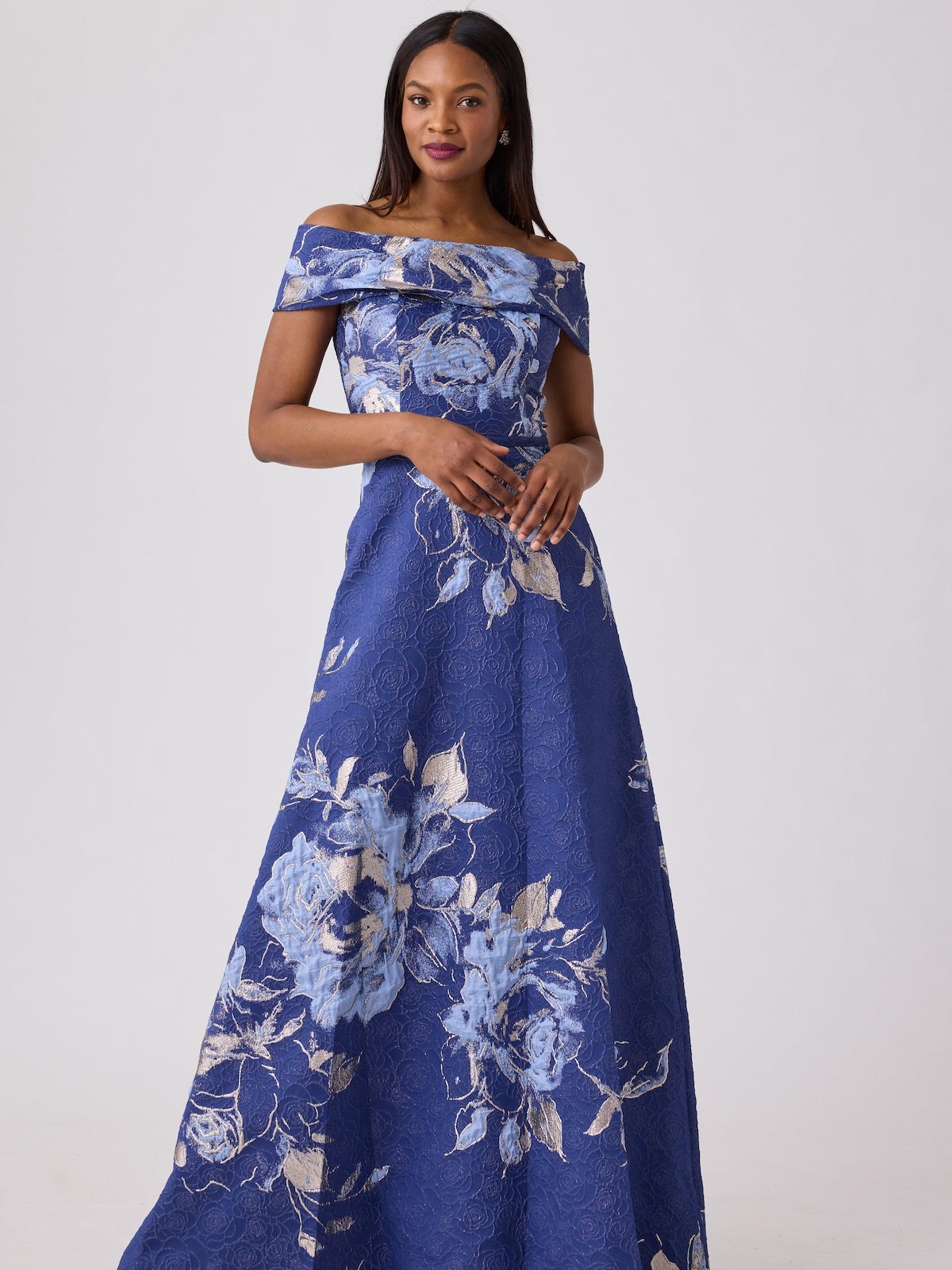Model in a blue floral jacquard off the shoulder ball gown