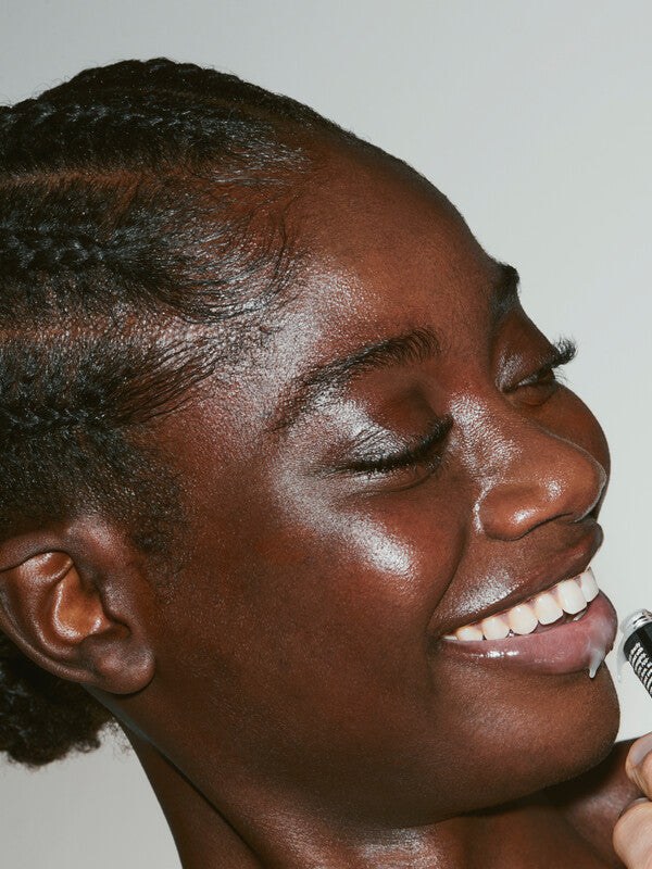 Smiling model with Grown Alchemist skincare in a close studio portrait