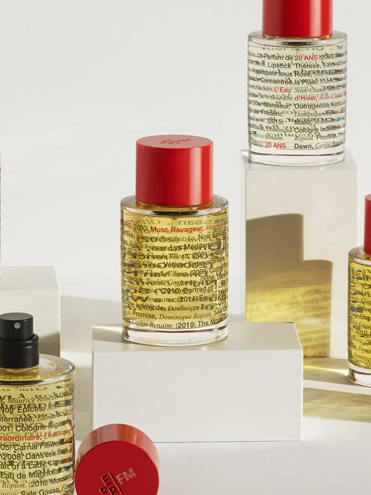 Red capped bottles arranged on white plinths