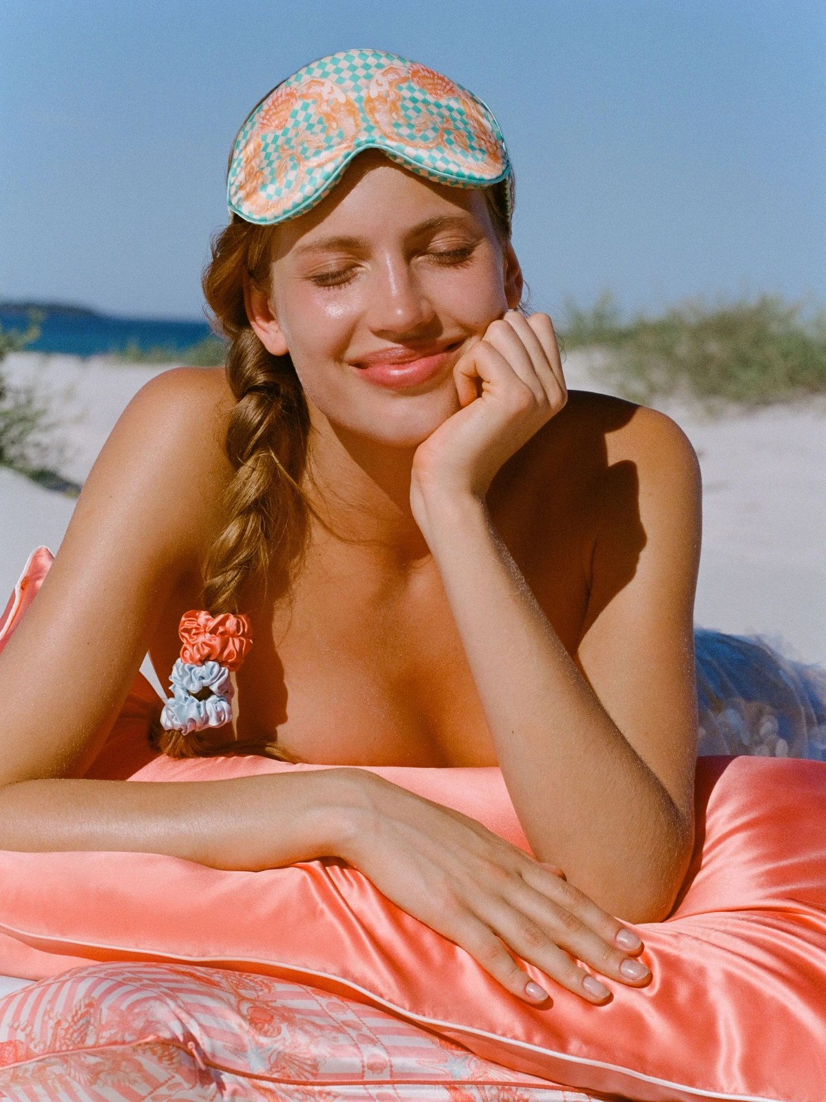 Model resting on a pink Slip pillow with a printed sleep mask