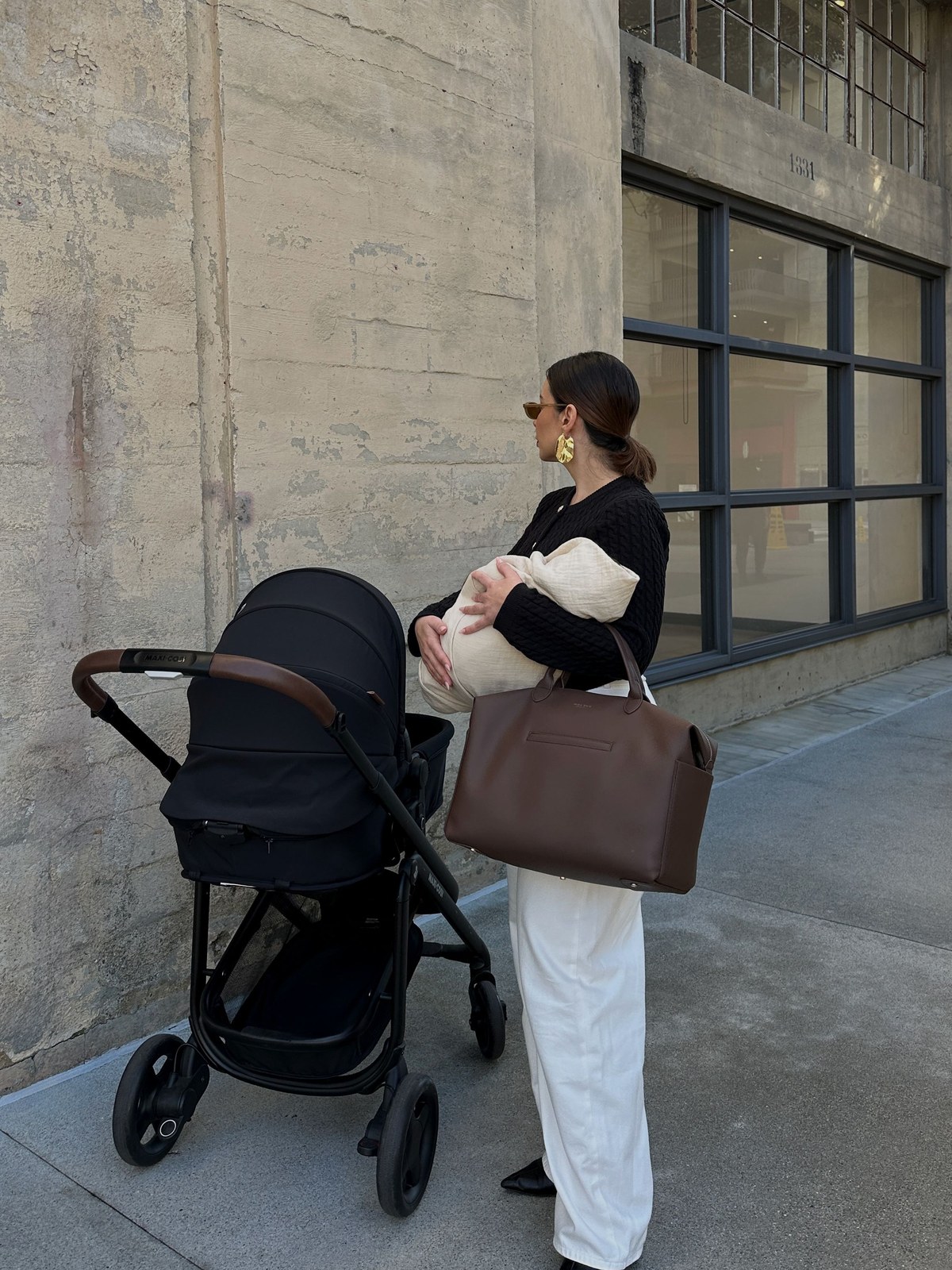 Parent with a black stroller outside a concrete building