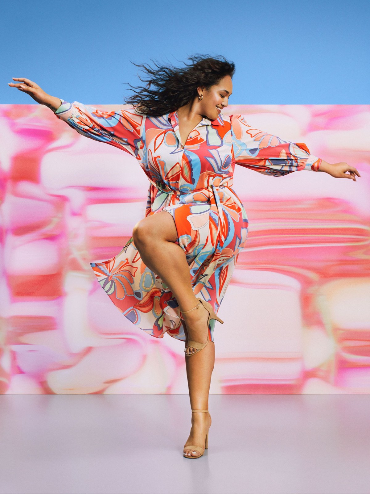 Model in a multicolored print ALEXIS for Target dress against a blue and pink set