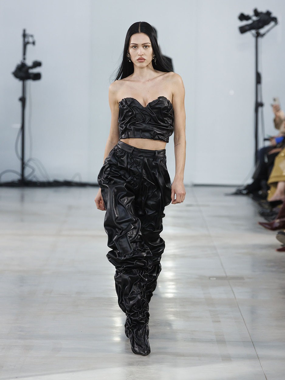 Model in a black sculptural look walking the Fall Winter 2025 runway