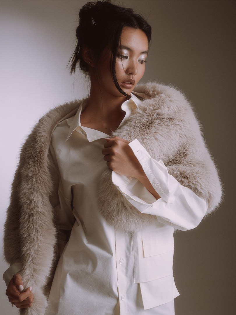 Model in a cream faux fur wrap over a white shirt