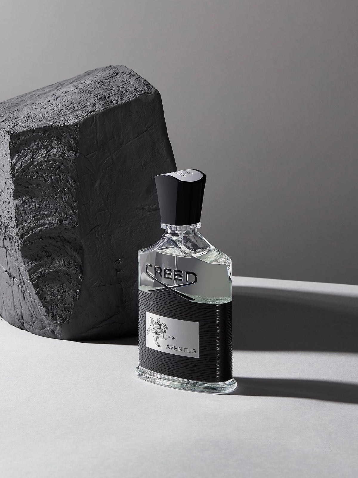 Aventus bottle next to a block of charcoal black stone