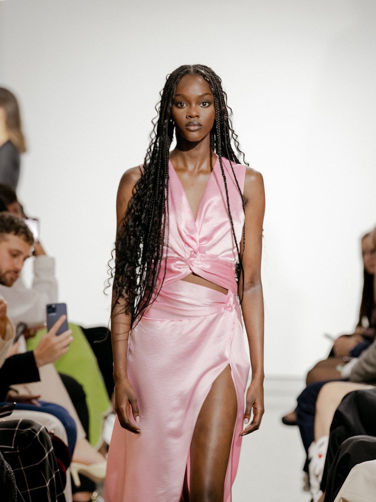 Runway model in a rose satin dress with a draped skirt