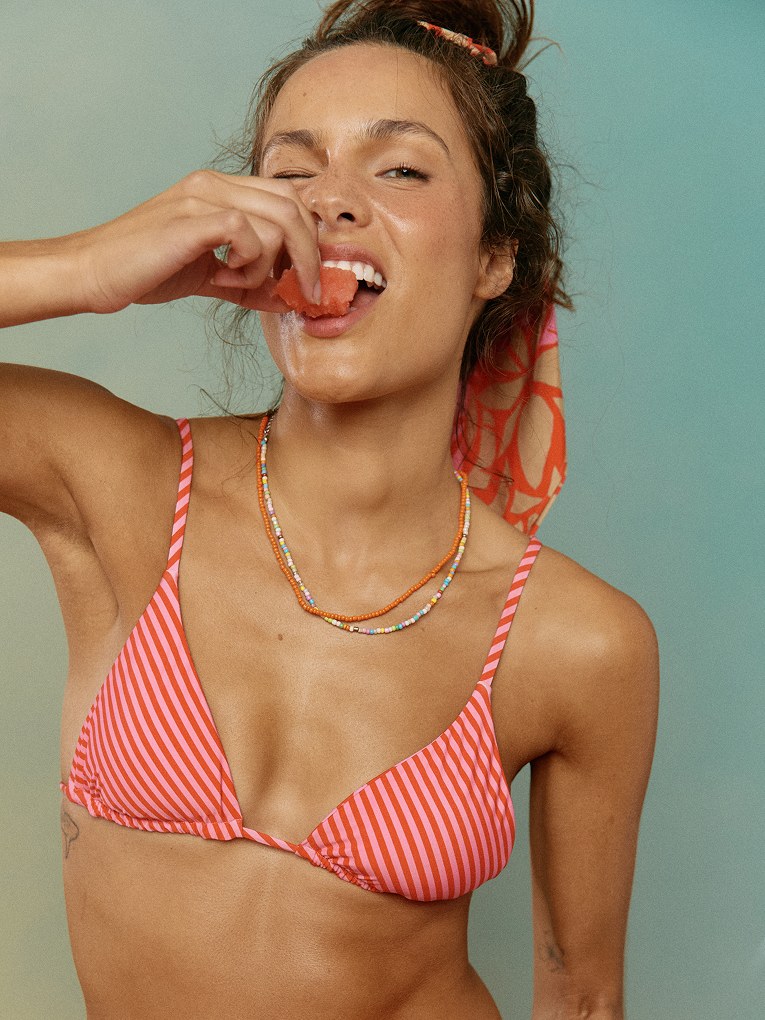 Model in a pink striped bikini enjoying a slice of watermelon