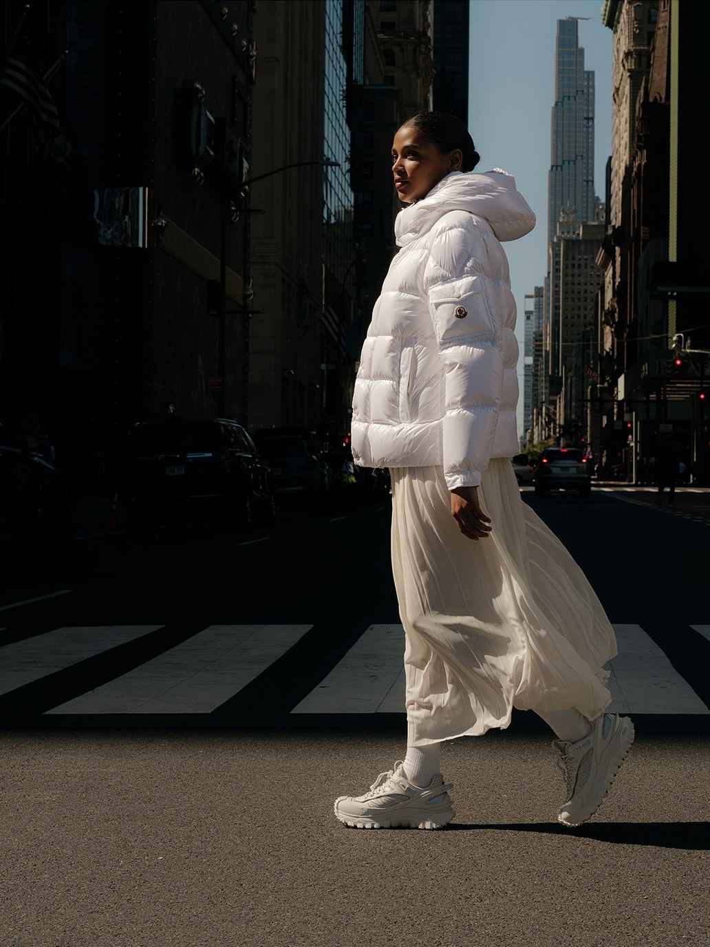 Moncler's fall 2026 New York campaign: a woman in a white Moncler down jacket crossing a Manhattan street