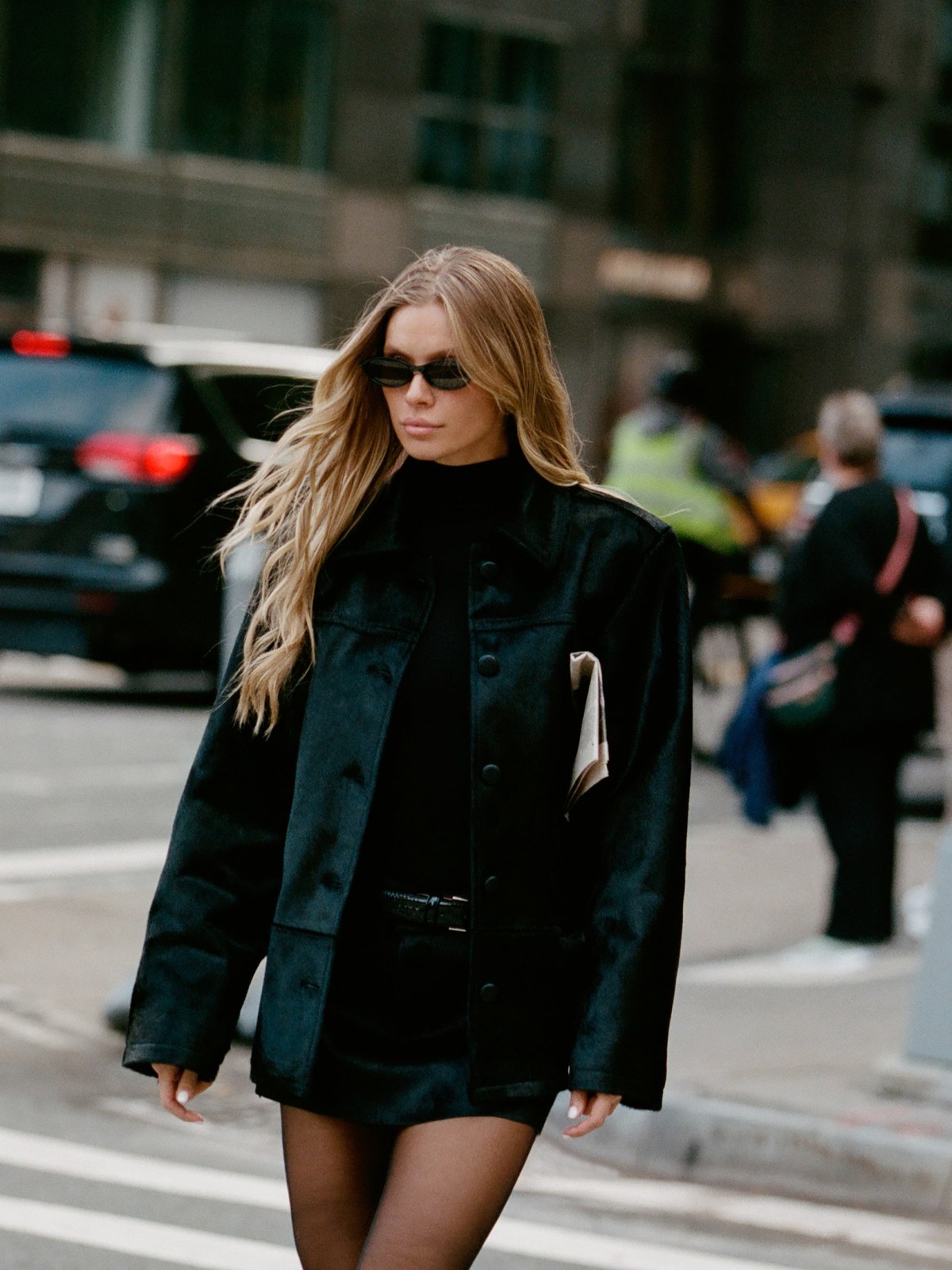 Model in a black fall jacket walking on a city street