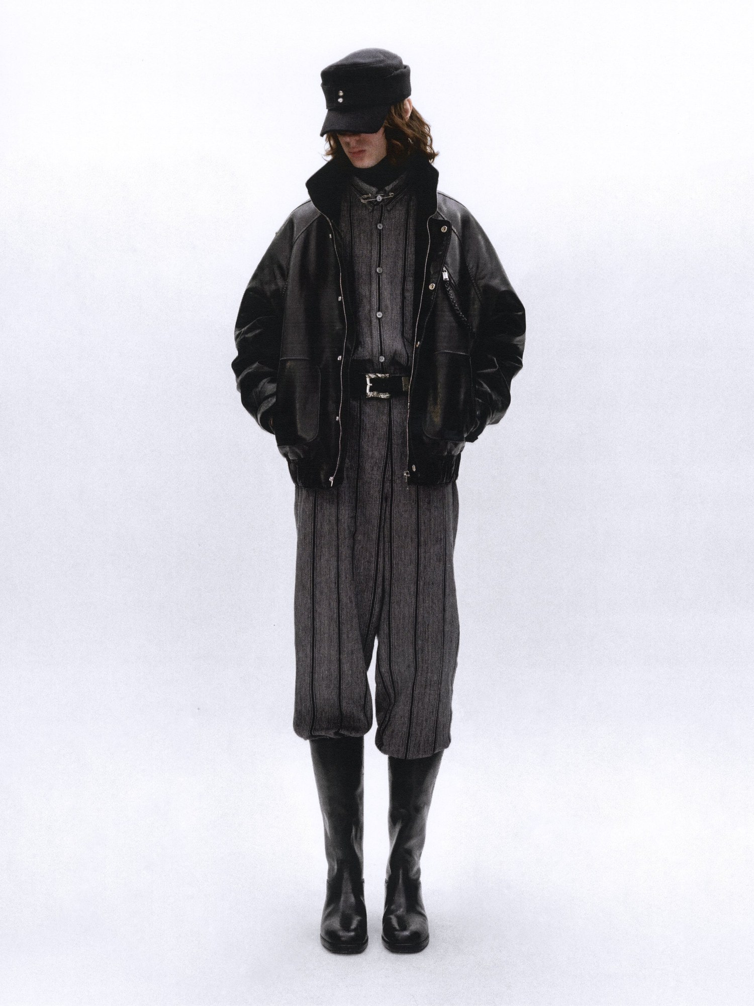 Model in a cap, leather jacket and striped trousers with boots