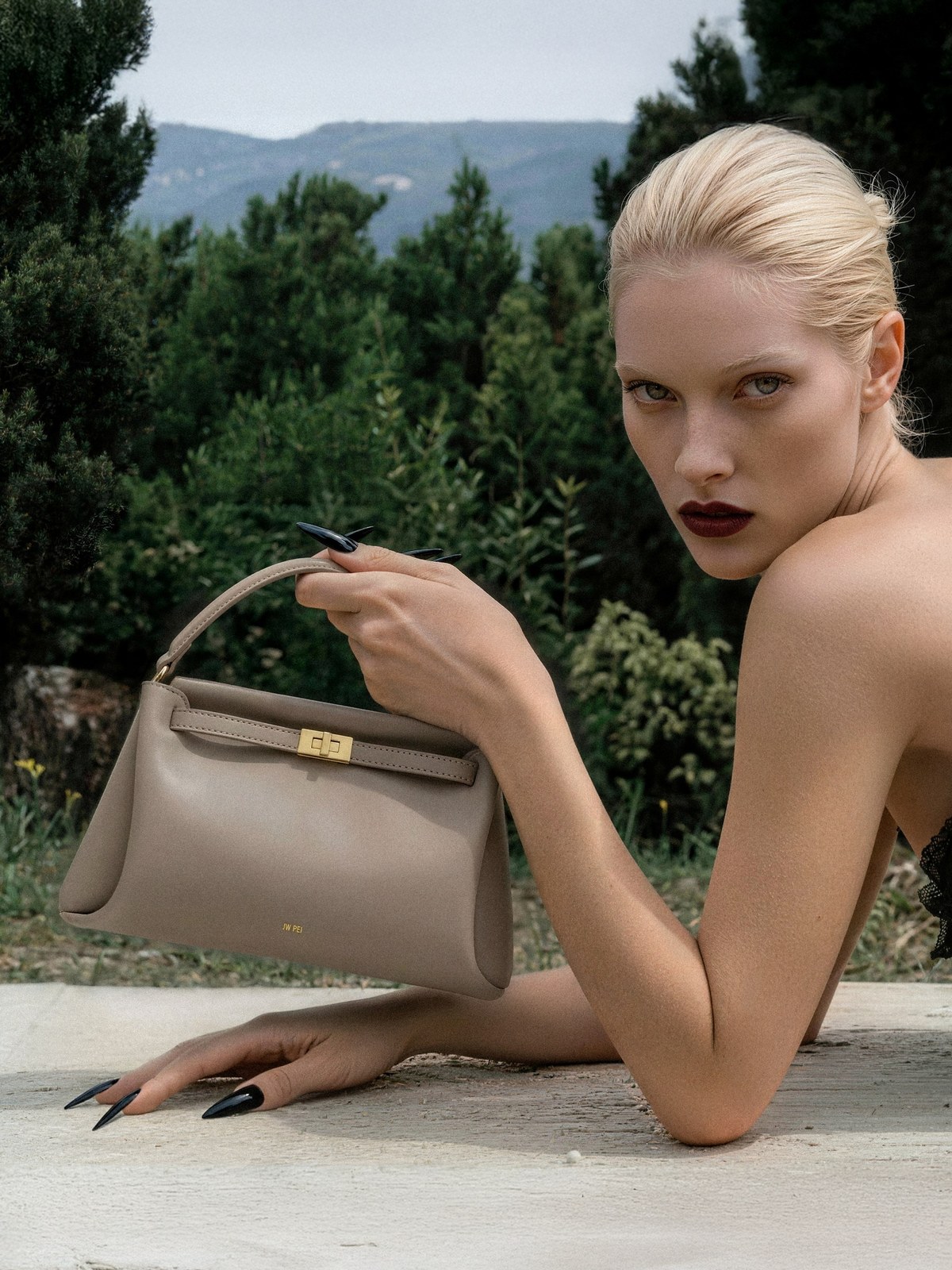 Woman outdoors carrying a taupe JW PEI top-handle bag
