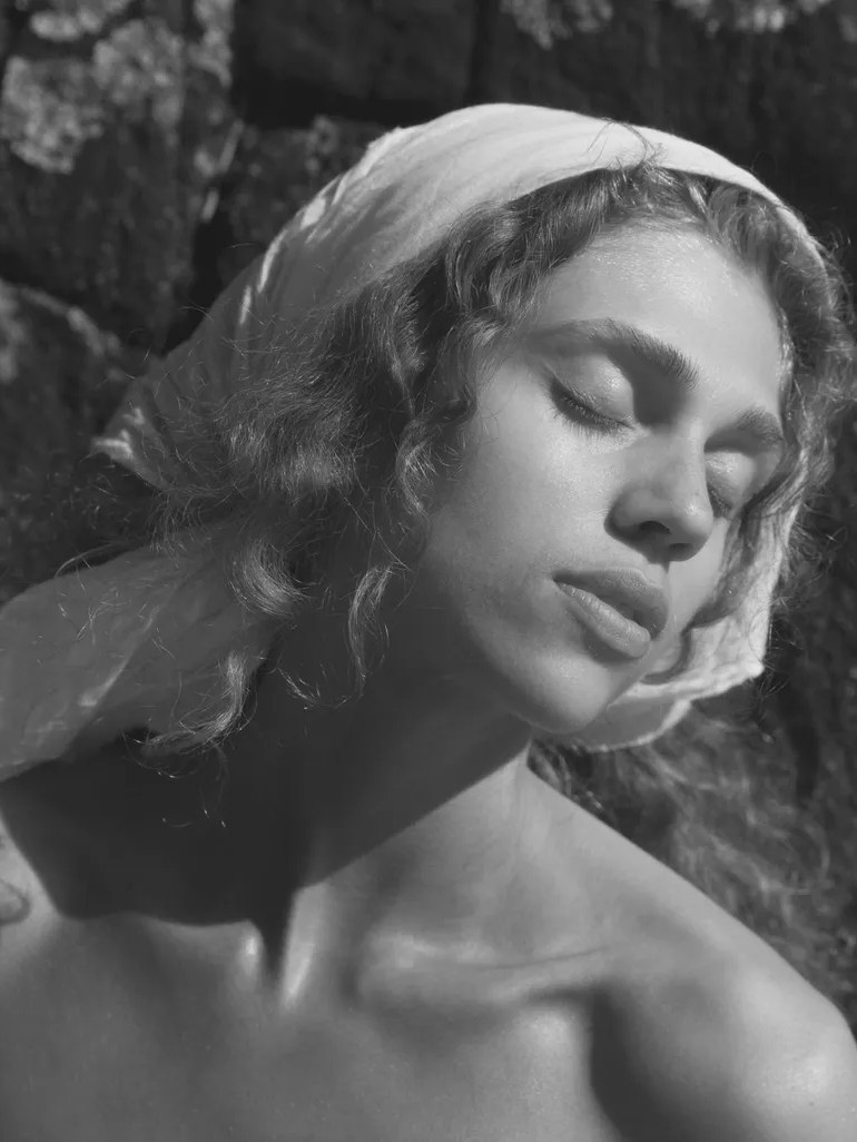 Black-and-white close-up portrait of a woman during a skincare ritual