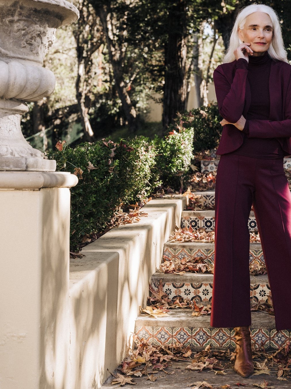 Silver-haired model in a burgundy Ripley Rader look on tiled garden steps