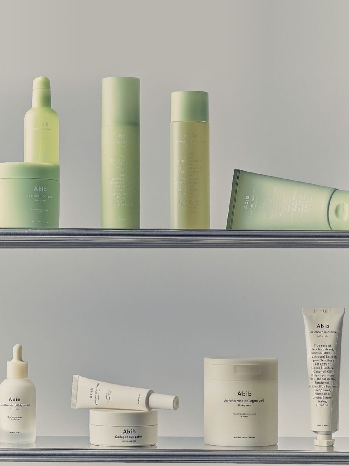 Abib skincare in pale green and cream bottles, pads, tubes and jars arranged on two glass shelves
