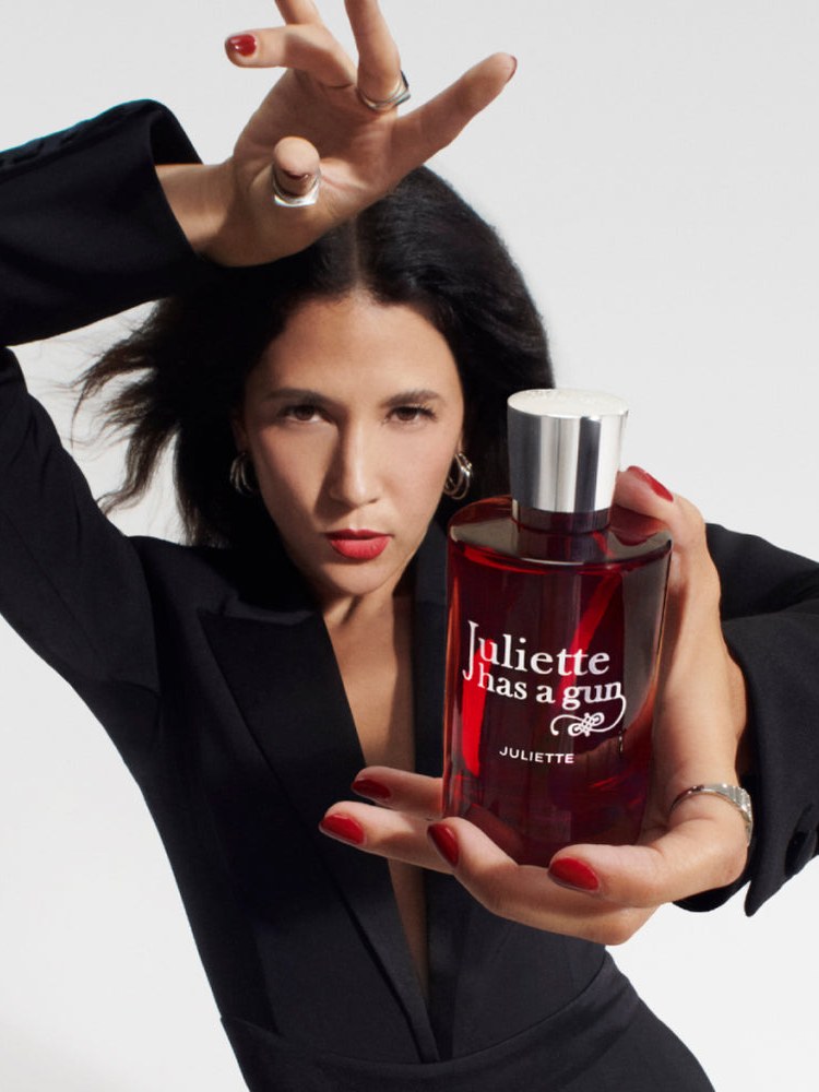 Model in a black outfit holding the red Juliette perfume bottle