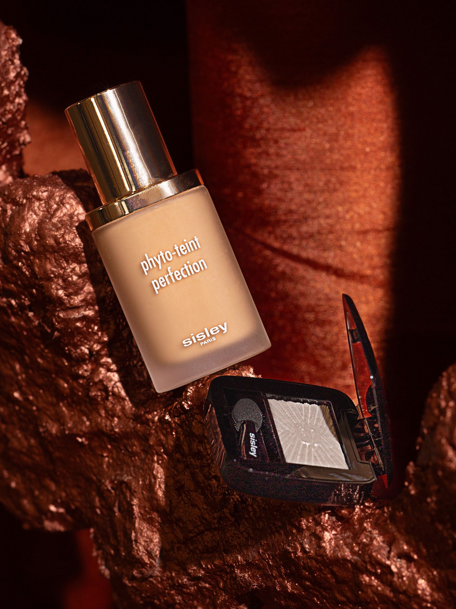 Phyto Teint Perfection foundation and an eyeshadow compact on a bronze sculpted rock