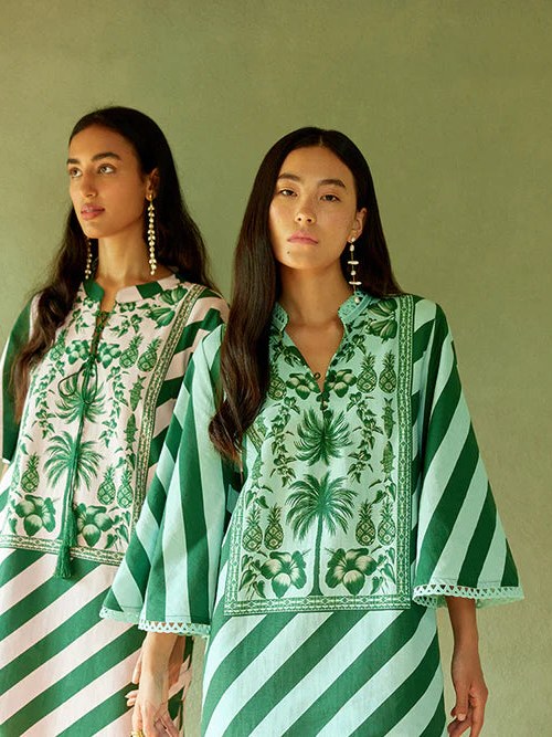 Two models in green botanical kaftans in a sunlit room