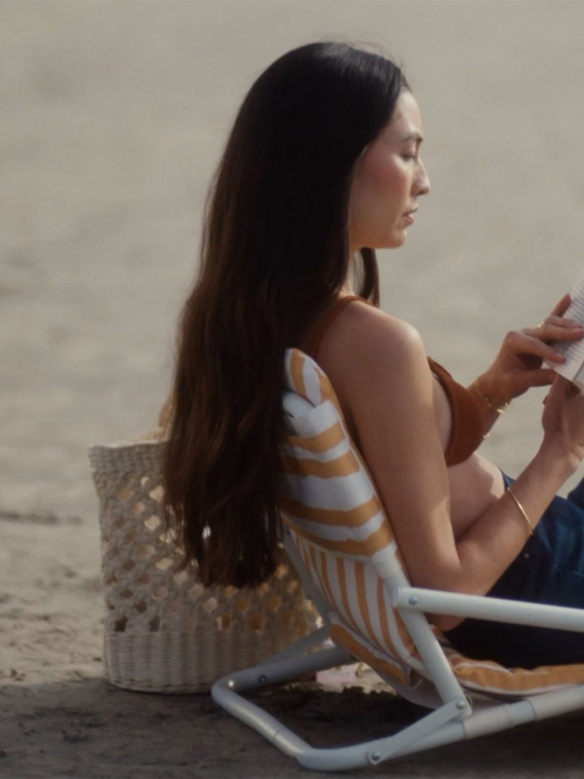 Jessica Mau reading in AG capri jeans on a beach