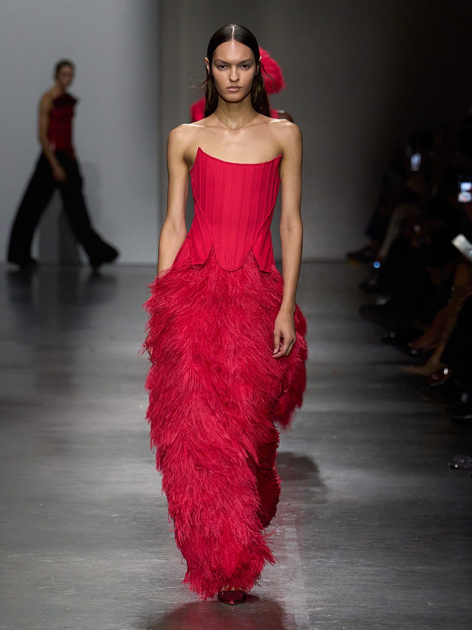 Model in a vivid red draped gown walking the Spring Summer 2026 runway