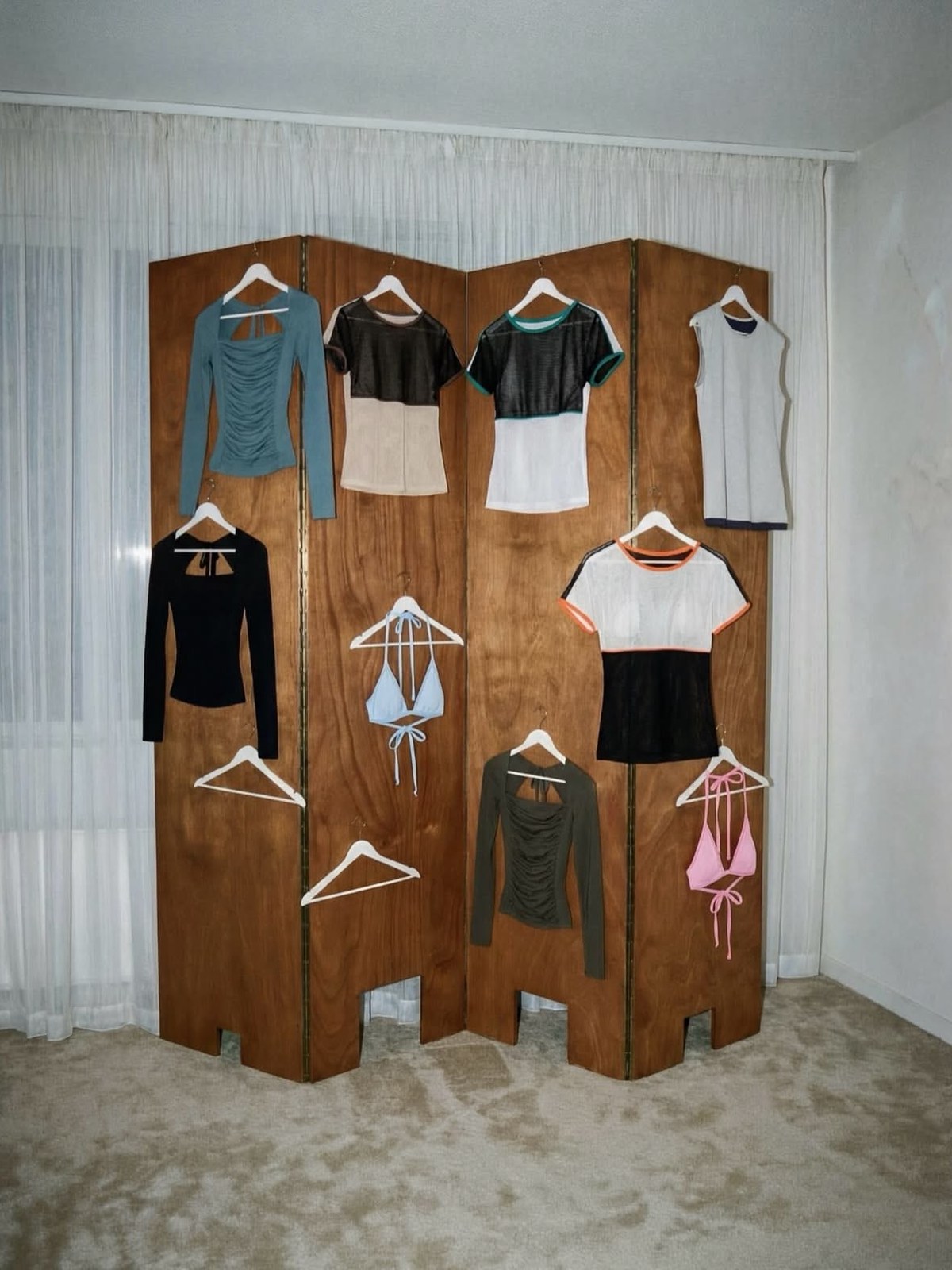 Tops and bikinis hung on a wooden folding screen