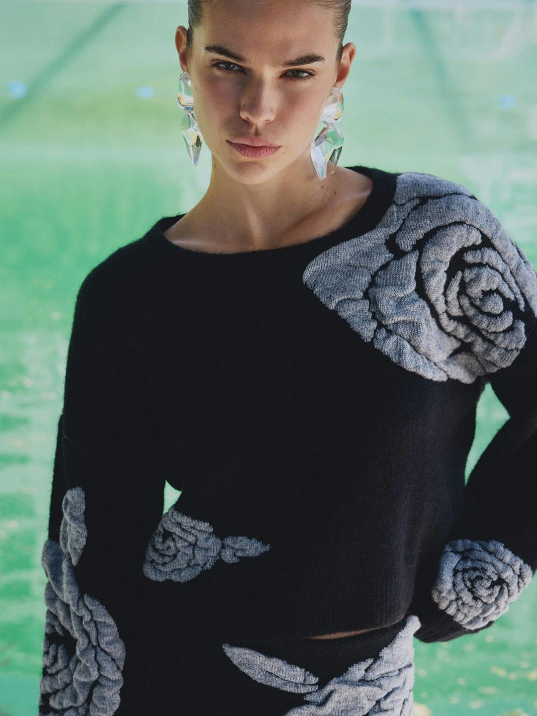 Model in a black sweater with large grey floral details