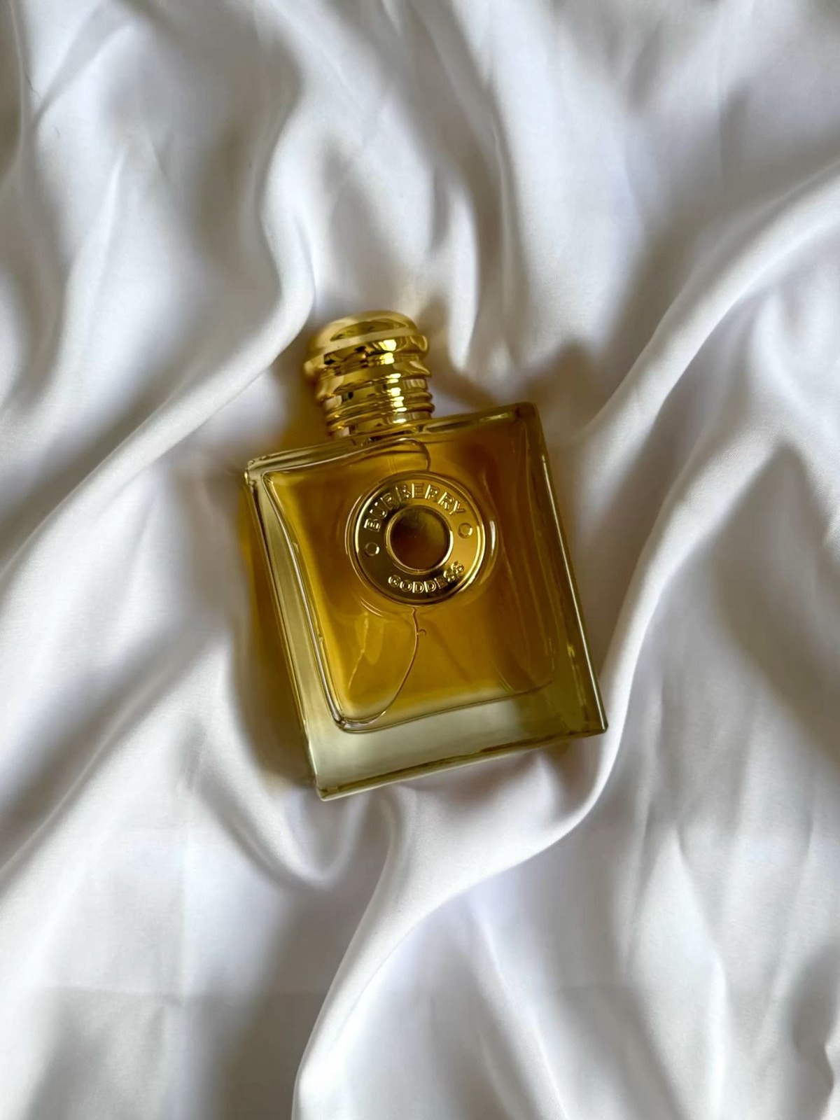 Burberry Goddess bottle resting in soft folds of white silk fabric
