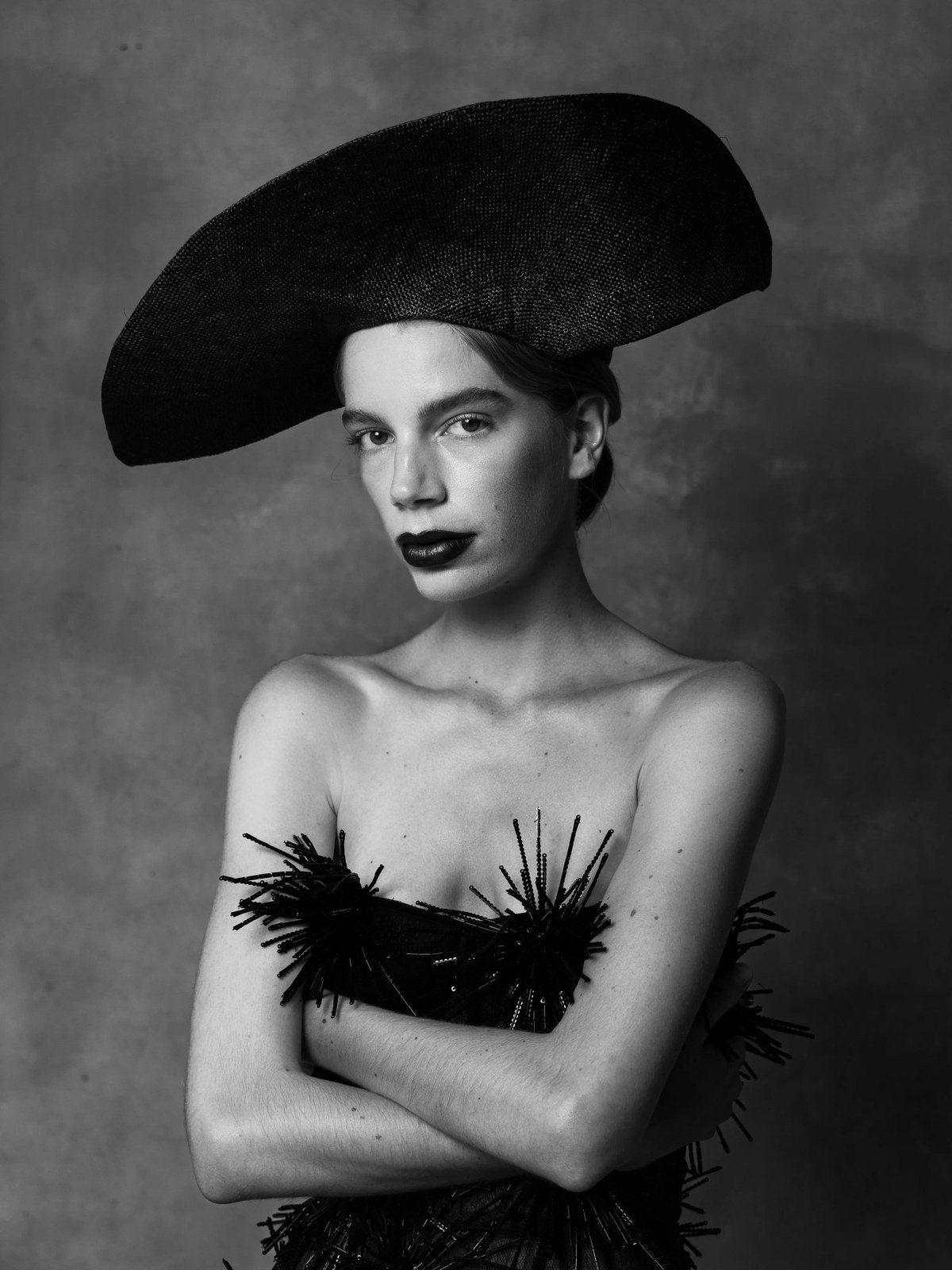 Close portrait of Vera Kuntz wearing a wide black hat and sculptural dress