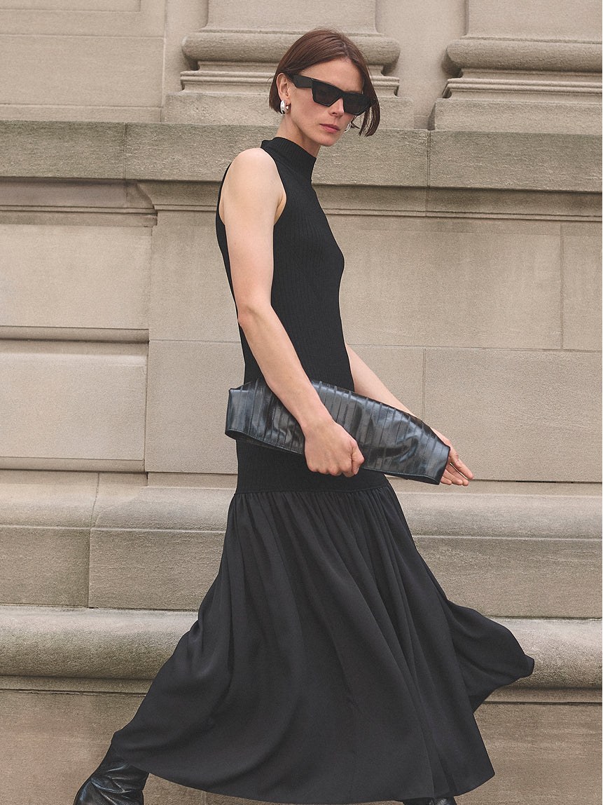 Model in a black dress walking past pale stone steps