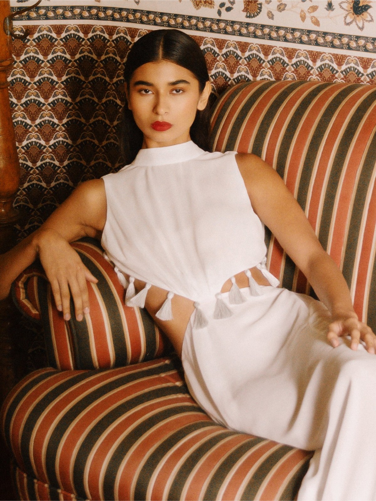 Model in an ivory AZULU dress seated on a striped sofa