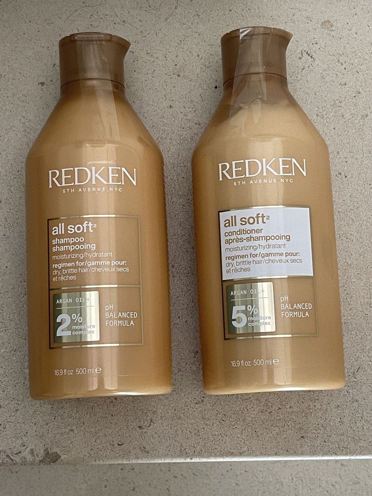 Three Redken Acidic Bonding Concentrate bottles arranged on a mirrored tray
