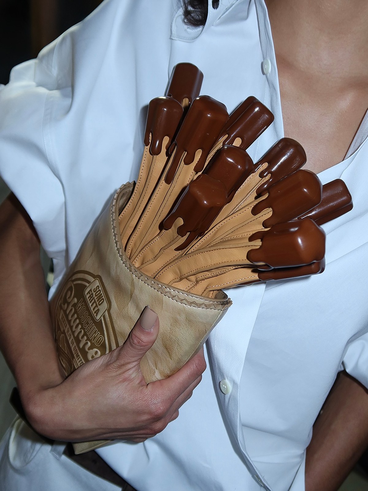 Model in a white shirt holding a churros shaped bag with chocolate sauce