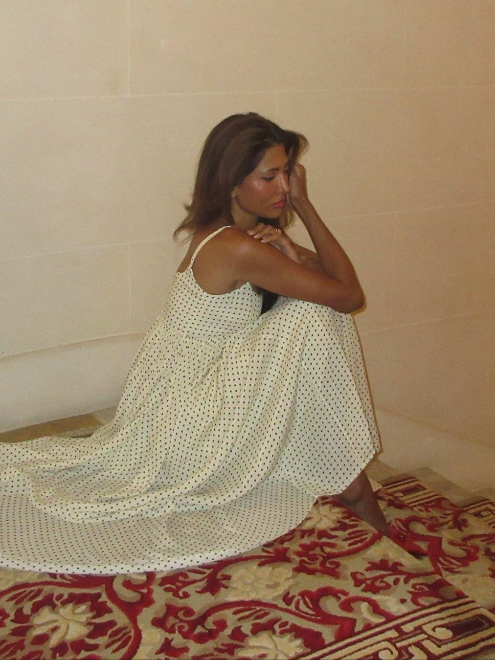 Model in a flowing white Azeeza gown seated in an ornate interior