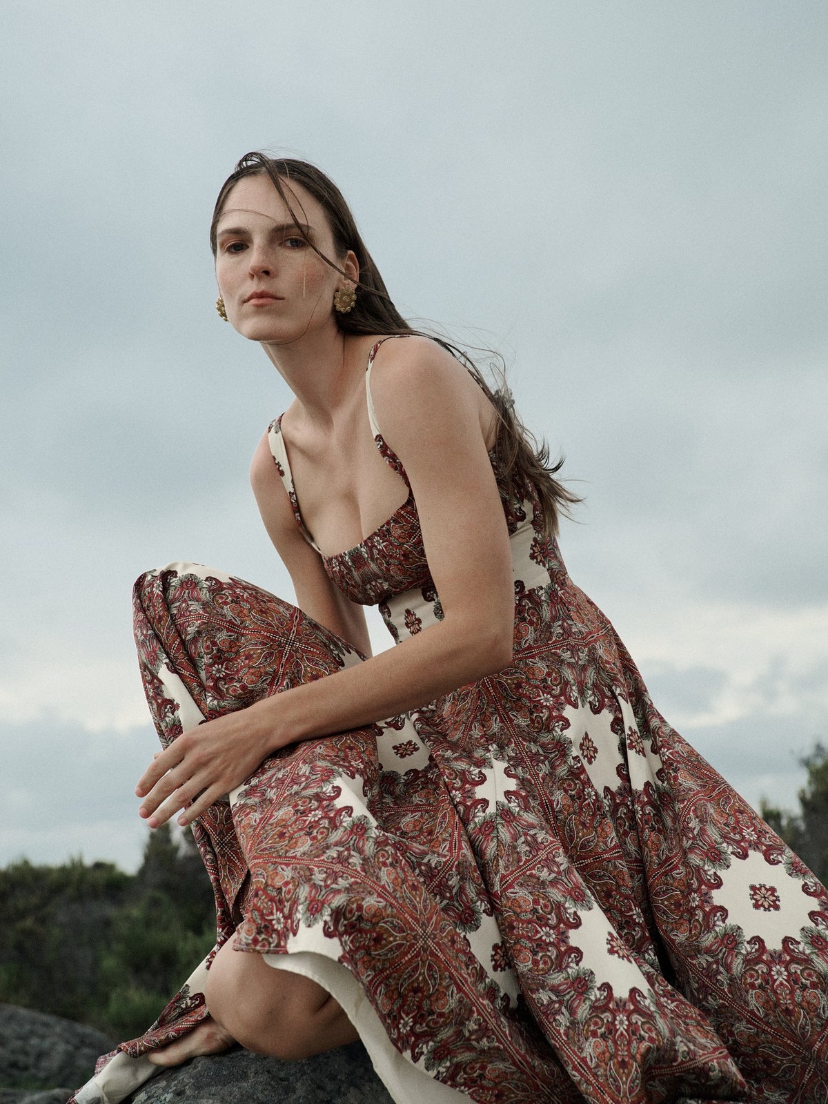 Model in a patterned CLEA dress seated in a garden