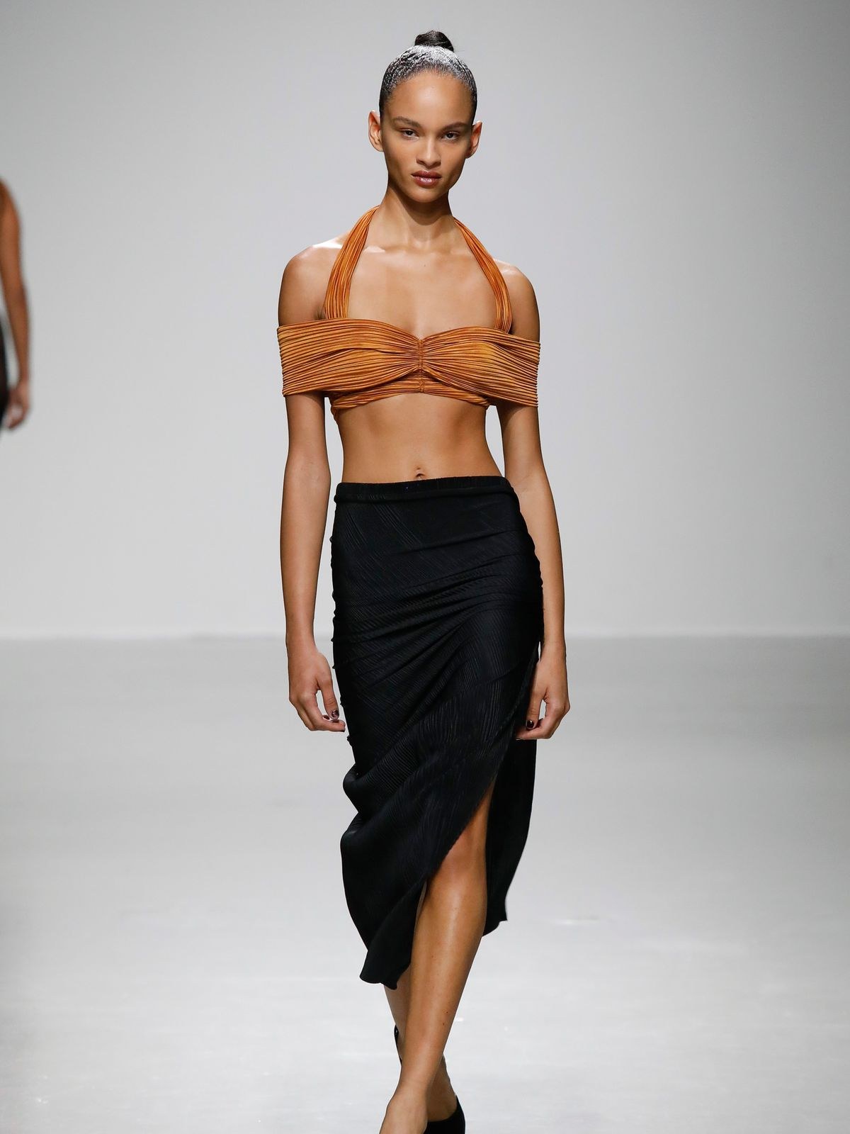 Model in a burnt orange Atlein halter top and black skirt
