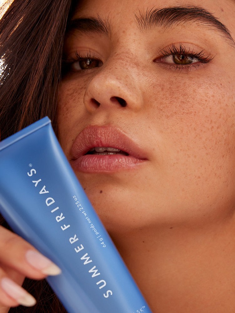 Close portrait of a woman holding the blue Jet Lag Mask tube