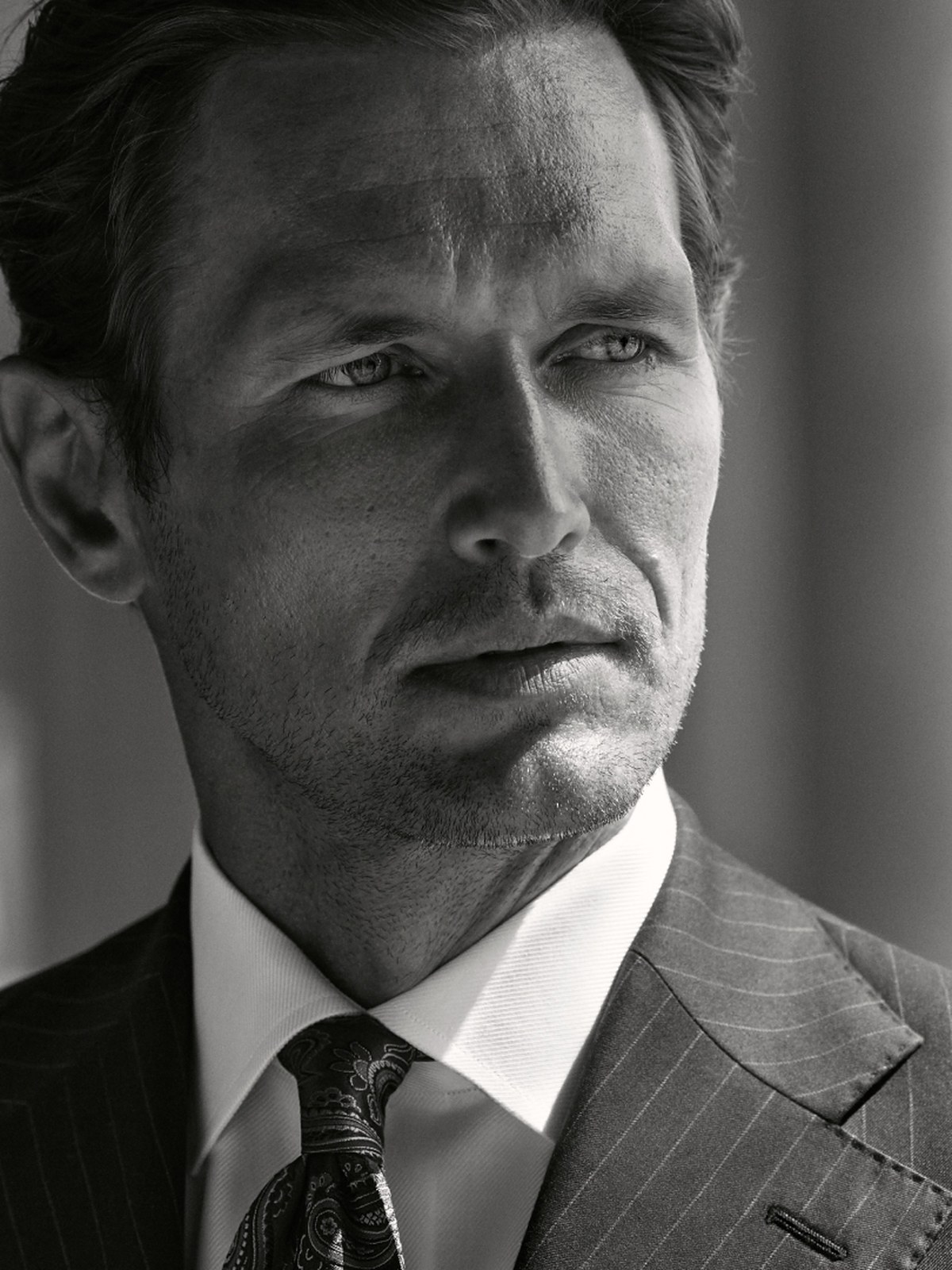 Black and white portrait of a man in a pinstripe suit and paisley tie