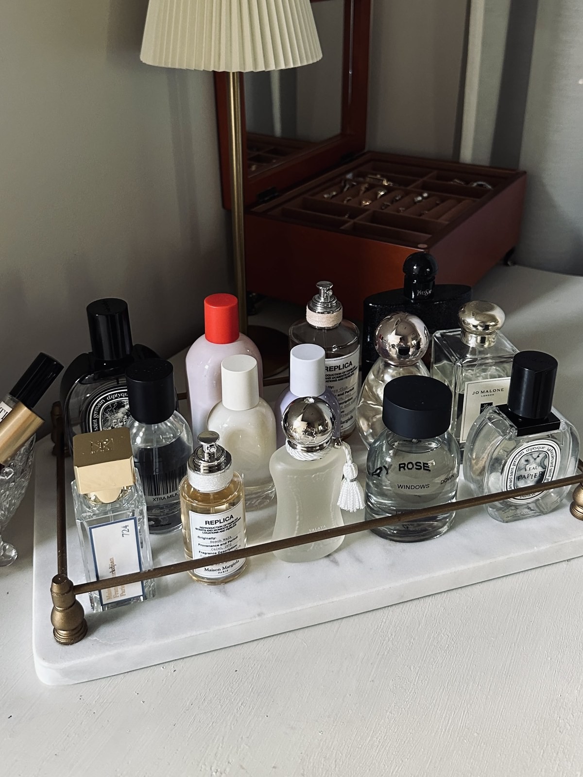 A row of perfume bottles on a marble tray in front of a mirror and jewelry box